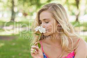 Side view of cute casual woman smelling a white flower