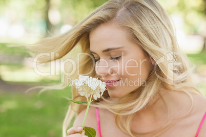 Gorgeous content woman smelling a flower with closed eyes