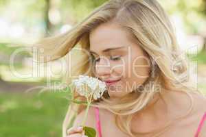 Gorgeous content woman smelling a flower with closed eyes