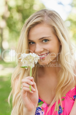 Pretty young woman smelling a white flower