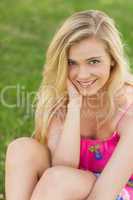 Portrait of cute young woman sitting on a lawn