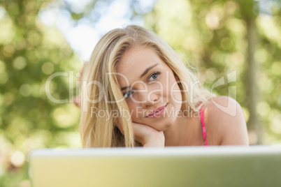 Day dreaming attractive woman lying in front of her notebook