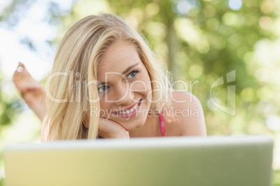 Happy day dreaming woman lying in front of her notebook