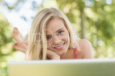 Joyful young woman lying in front of her notebook