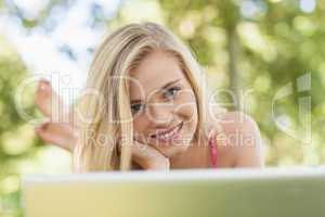Joyful young woman lying in front of her notebook