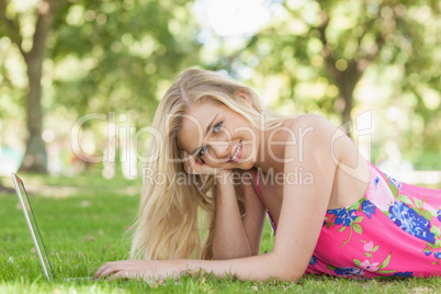 Portrait of gorgeous woman using her notebook lying on a lawn