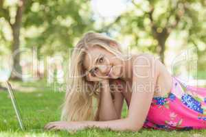 Portrait of gorgeous woman using her notebook lying on a lawn