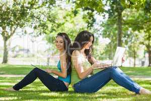 Young brunette woman sitting with her friend on a lawn