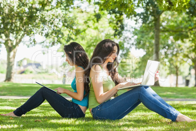 Two young brunette women sitting on a lawn