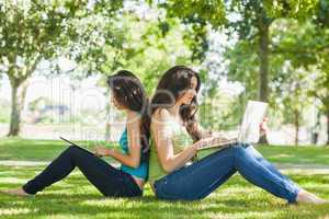 Two young brunette women sitting on a lawn