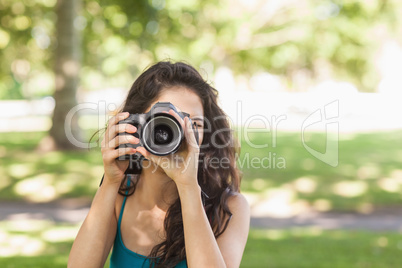 Front view of cute brunette woman taking a picture with her came