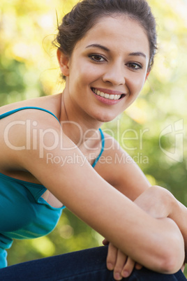 Side view of young brunette woman sitting on a lawn
