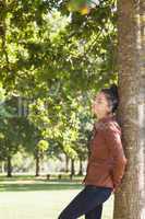 Attractive woman leaning against a tree with closed eyes