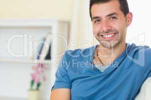 Casual smiling man relaxing on couch looking at camera