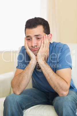 Casual sad man sitting on couch