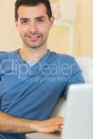 Casual happy man sitting on couch using laptop