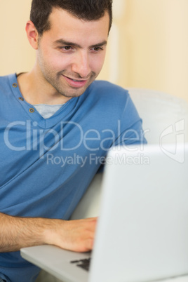 Casual content man sitting on couch using laptop