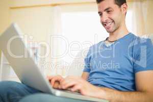 Casual attractive man sitting on couch using looking at laptop