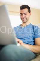 Casual handsome man sitting on couch using looking at laptop