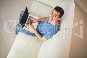 High angle view of casual smiling man using laptop