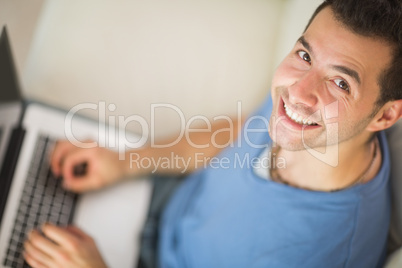 High angle view of casual cheerful man using laptop
