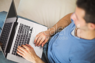 High angle view of casual man using laptop sitting on couch
