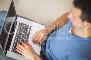 High angle view of casual man using laptop sitting on couch