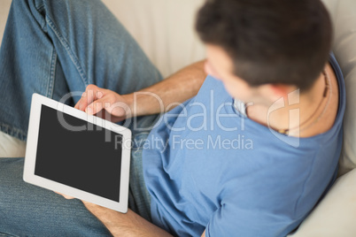 High angle view of casual man using tablet sitting on couch