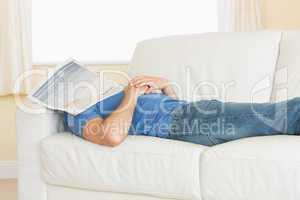 Casual man sleeping on couch with newspaper on his head