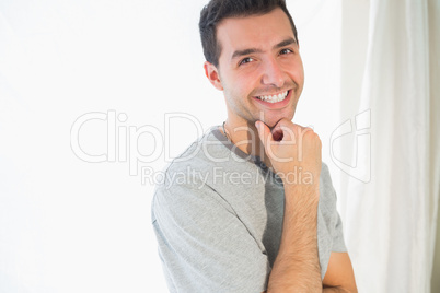 Casual smiling man looking at camera touching chin