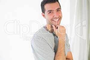 Casual smiling man looking at camera touching chin
