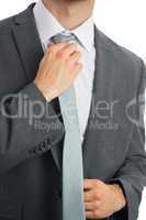 Close up of businessman adjusting blue tie