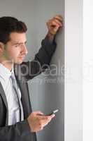 Handsome frowning businessman holding smartphone