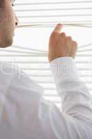 Attractive businessman spying through roller blind