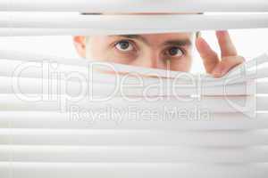 Suspicious male eyes spying through roller blind