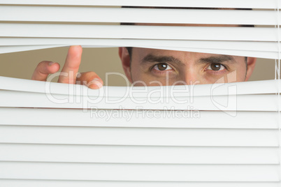 Focused male eyes spying through roller blind