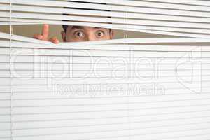 Shocked male eyes spying through roller blind