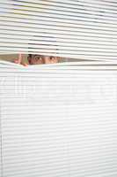 Astonished male eyes spying through roller blind