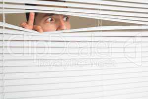 Scared male eyes spying through roller blind