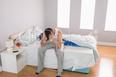 Tired casual man sitting on bed