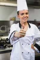 Young smiling chef looking at camera showing thumb up