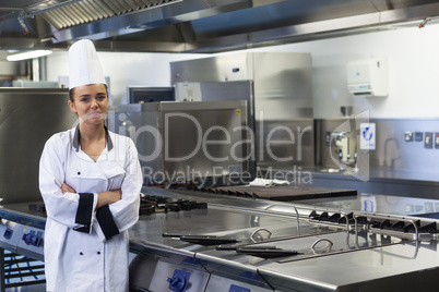 Young happy chef standing next to work surface arms crossed