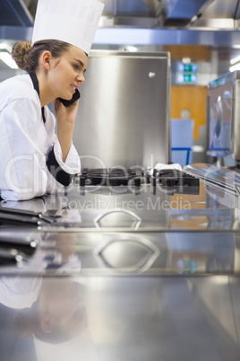 Young gorgeous chef standing next to work surface phoning