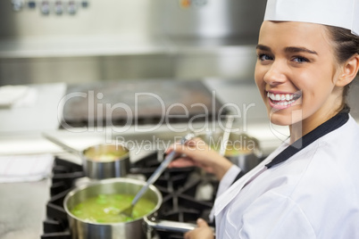 Young cheerful chef stirring sauce