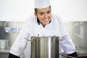 Young smiling chef standing behind saucepan