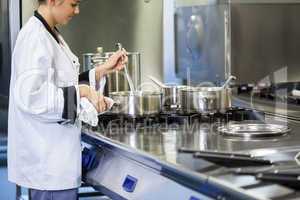 Young chef stirring with ladle