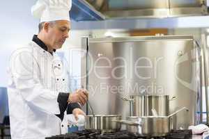 Focused head chef stirring in pot
