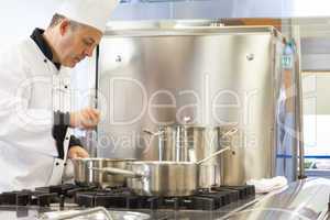 Concentrated head chef stirring in pot