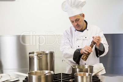 Focused head chef using pepper mill