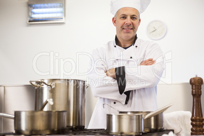 Smiling head chef standing arms crossed behind pot